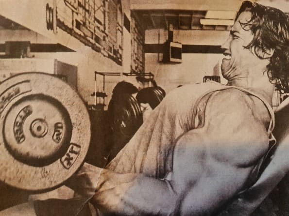 Arnold Schwarzenegger benching a very heavy weight
